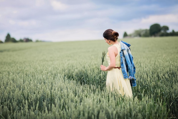 Styl życia portret młodej stylowej kobiety idącej przez pole pszenicy