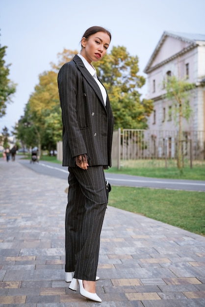 Stylowa bizneswoman brunetka rasy kaukaskiej z pięknym makijażem pozuje na ulicy w...