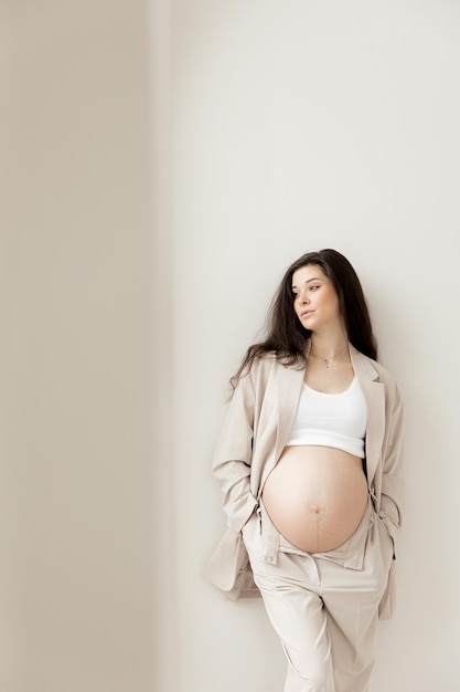Stylowa brunetka w ciąży w beżowym garniturze