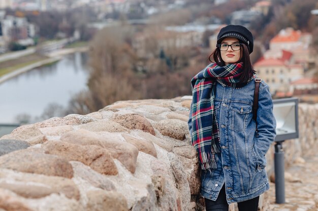 Stylowa dziewczyna w dżinsowej kurtce chodzi przy Vilnius tłem