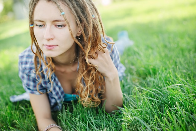 Stylowa dziewczyna z dredami na trawie