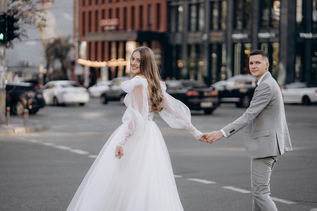 Stylowa europejska para nowożeńcy przechodzą przez ulicę Kobieta trzyma męską dłoń idącą z