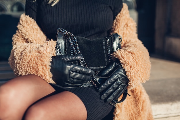 Zdjęcie stylowa kobieta nosi płaszcz i trzyma czarną torebkę na zewnątrz