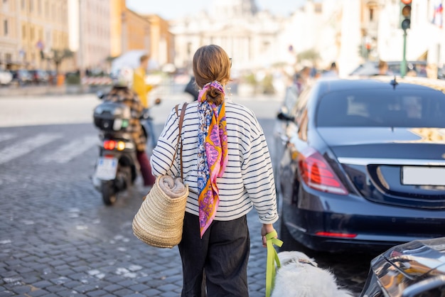 Stylowa kobieta spaceruje z psem po ulicy w Rzymie