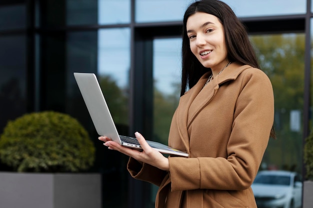 Stylowa kobieta stojąca na zewnątrz za pomocą laptopa Businesswoman pracuje na ulicy zakupy online