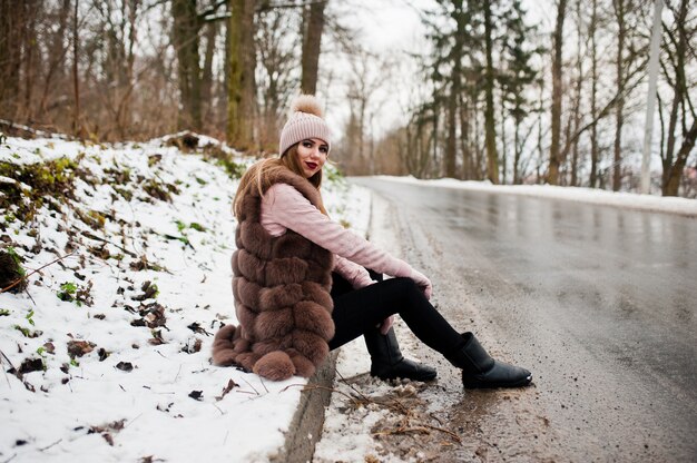 Stylowa kobieta w futrze i nakrycia głowy w zimowy dzień na siedzącej granicy ofroad.