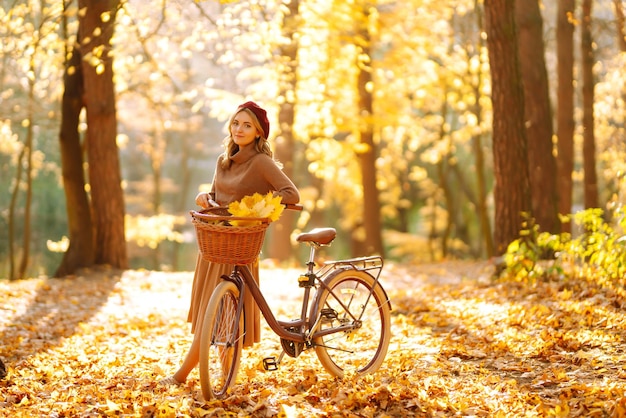 Stylowa kobieta z rowerem, ciesząc się jesienną pogodą w parku Piękna kobieta w lesie jesienią
