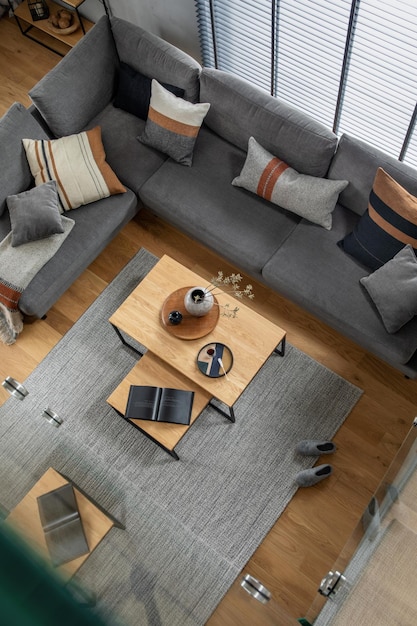 Stylowa kompozycja wnętrza salonu z narożną szarą sofą zielony aksamitny fotel stolik kawowy drewniana podłoga projekt meble i minimalistyczne akcesoria osobiste Nowoczesny wystrój domu Szablon