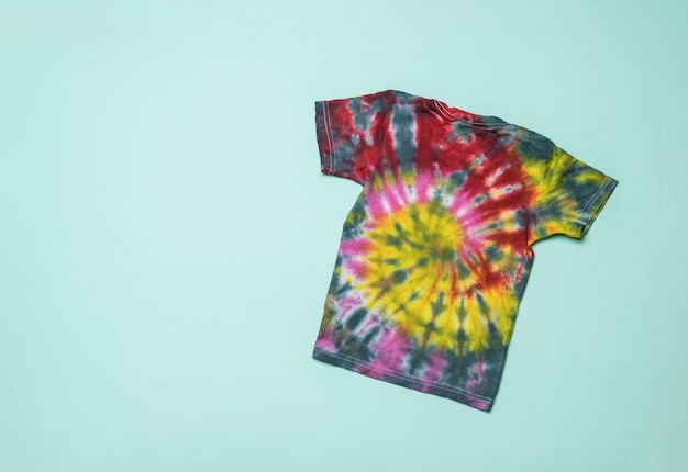 Stylowa koszulka tie dye na jasnoniebieskim tle. Kolorowanie ubrań ręcznie w domu. Leżał płasko.