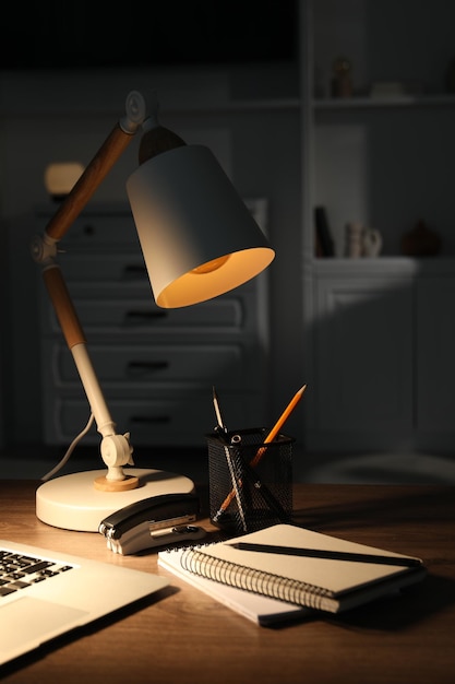 Stylowa lampa i artykuły biurkowe na drewnianym stole w pomieszczeniu