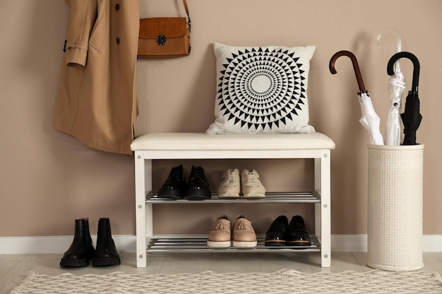 Zdjęcie stylowa ławka do przechowywania z różnymi parami butów przy beżowej ścianie w przedpokoju