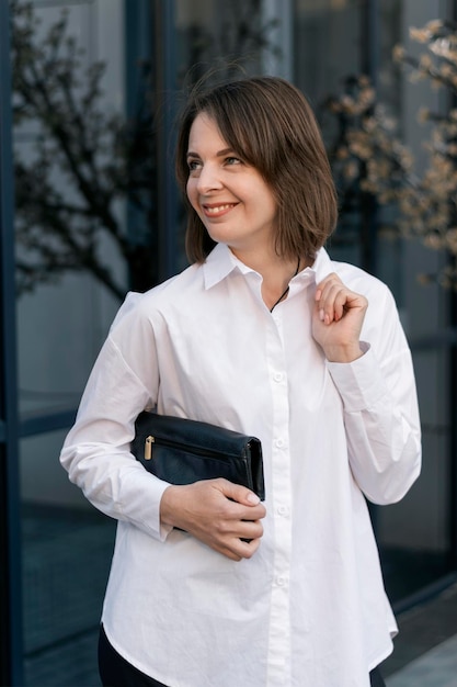 Stylowa młoda kobieta w oficjalnej odzieży biznesowej Formalna koszula i czarne sprzęgło Styl casual