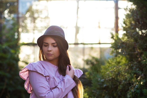 Stylowa opalona dziewczyna ubrana w modną bluzkę i kapelusz, pozowanie na zewnątrz w świetle słonecznym. Pusta przestrzeń