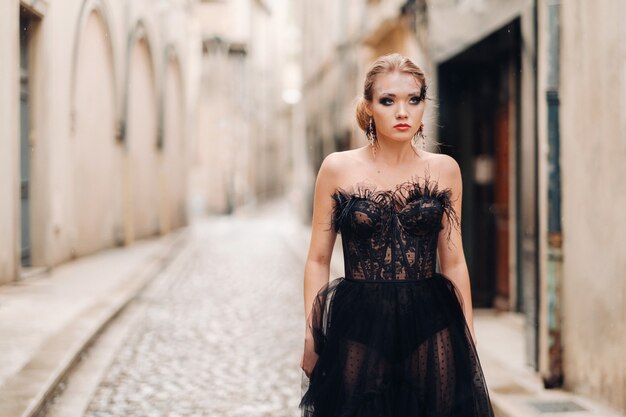 Stylowa panna młoda w czarnej sukni ślubnej pozuje w starożytnym francuskim mieście Awinion. Modelka w pięknej czarnej sukience. Sesja zdjęciowa w Prowansji.