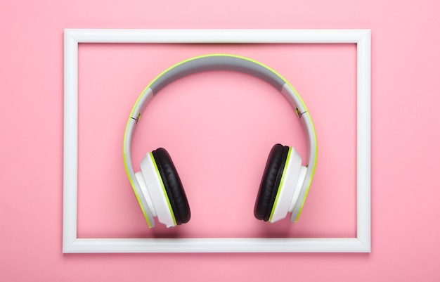 Stylowe bezprzewodowe słuchawki stereo na różowej, pastelowej powierzchni z białą ramką