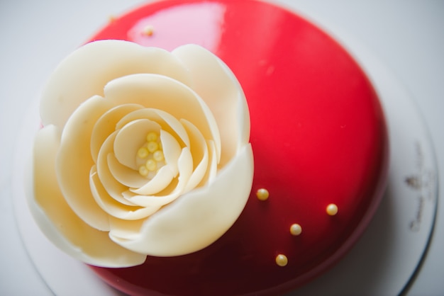 Stylowe Czerwone Ciasto Z Białą Różą. Czerwone Ciasto Z Dużym Kwiatkiem Białej Czekolady. Tort Urodzinowy