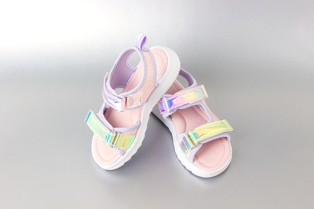 Stylowe holograficzne sandały dla dzieci na szarym tle Błyszczące modne buty na lato