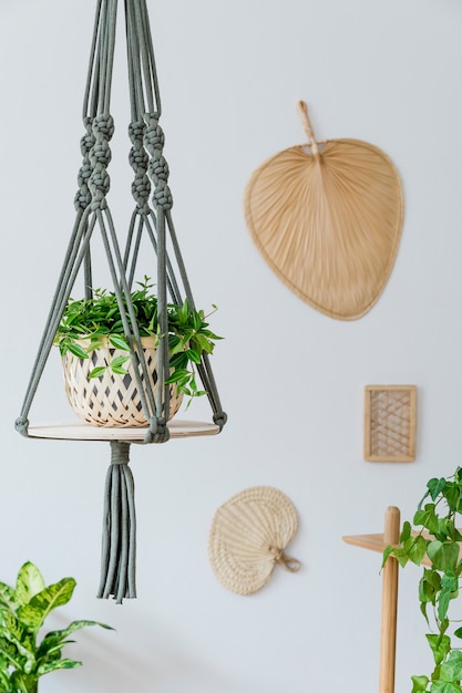 Zdjęcie stylowe i boho domowe wnętrze otwartej przestrzeni z drewnianym biurkiem, krzesłem, lampą i białą półką. design i eleganckie akcesoria osobiste. botanika i minimalizm. wystrój domu. malarstwo abstrakcyjne na ścianie