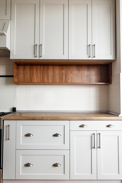 Stylowe jasnoszare wnętrze kuchni z nowoczesnymi szafkami i uchwytami ze stali nierdzewnej Projekt kuchni w stylu skandynawskim Współczesny drewniany blat kuchenny i komin