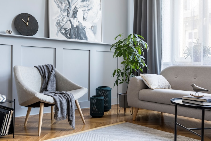 Zdjęcie stylowe skandynawskie wnętrze salonu z designerską szarą sofą, fotelem, marmurowym taboretem, czarnym stolikiem kawowym, nowoczesnymi obrazami, dekoracjami, roślinami i eleganckimi akcesoriami osobistymi w wystroju domu.