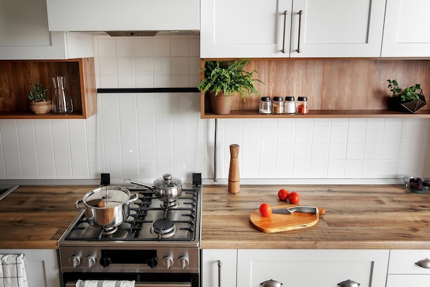 Stylowe wnętrze kuchni z nowoczesnymi szafkami i urządzeniami ze stali nierdzewnej w nowym projekcie domu w stylu skandynawskim gotowanie żywności zielone rośliny wystrój drewniany blat zlewozmywak i kuchenka