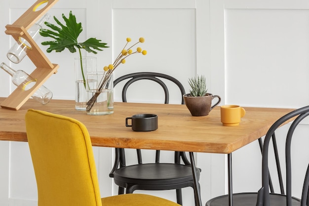 Stylowe żółte krzesło przy drewnianym stole w modnym wnętrzu
