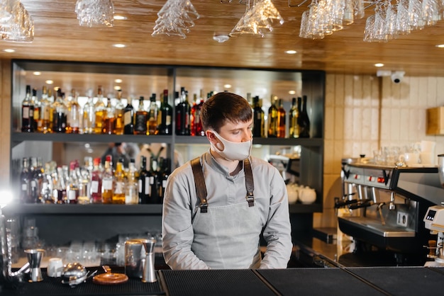 Stylowy barman w masce i mundurze podczas pandemii. Praca restauracji i kawiarni podczas pandemii.