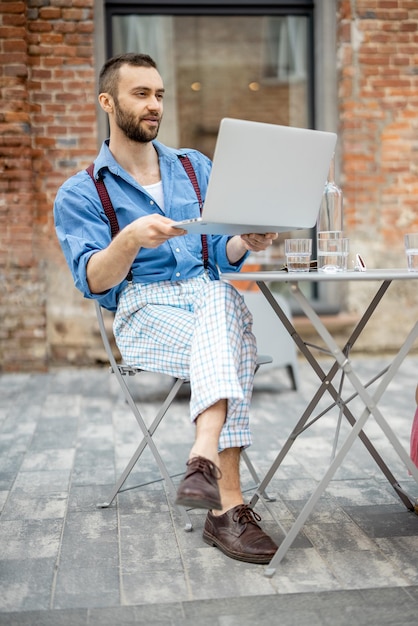 Stylowy biznesmen rozmawia online na laptopie w kawiarni