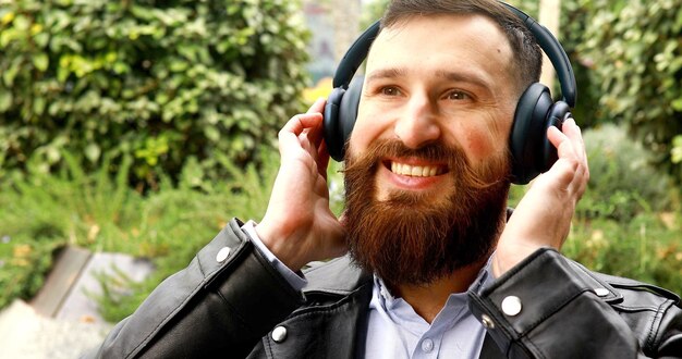 Stylowy brodaty mężczyzna słucha muzyki w słuchawkach.