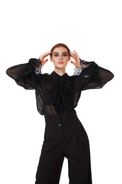 Stylowy ładny młoda kobieta w czarnej eleganckiej bluzce i kapeluszu na białym jasnym tle. Kobieta w modnych ubraniach pozuje do kamery. Koncepcja stylu, mody, piękna i realizacji celów