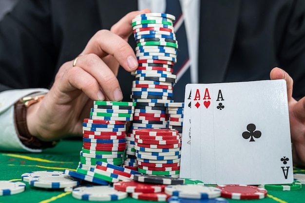 Stylowy mężczyzna w czarnym garniturze trzymający karty do gry i żetony do pokera w kasynie Koncepcja gry hazardowej