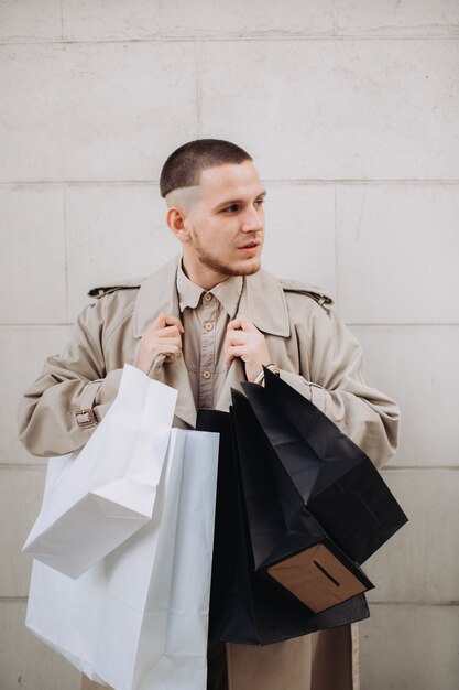 Stylowy młody człowiek z torbami po udanych zakupach w Czarny piątek
