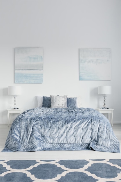 Stylowy projekt sypialni z łóżkiem typu king-size, białymi stolikami nocnymi z lampkami i wzorzystym dywanikiem prawdziwe zdjęcie