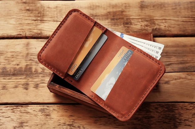 Stylowy skórzany portfel z pieniędzmi i pudełkiem na drewnianym tle