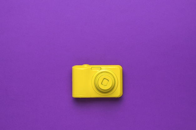 Stylowy żółty aparat retro na fioletowym tle. Leżał płasko.