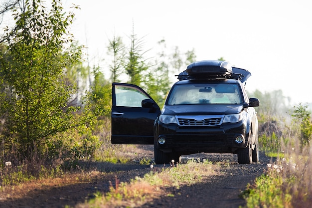 Subaru Forester z boxem dachowym na polnej drodze w lesie