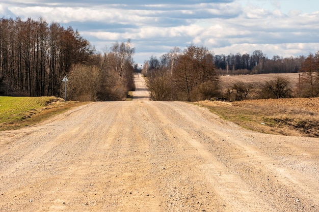 Sucha piaszczysta droga przechodzi przez pole pod palącym słońcem i chmurami Droga gruntowa za miastem we wsi Suchy klimat na ziemi Zmiana klimatu i jej konsekwencje