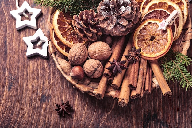 Sucha pomarańcza, anyż, cynamon, szyszki i jodły w rustykalnym talerzu na drewnianym stole. Domowa składanka na świąteczny nastrój i aromat. Ekologiczne święta z domowymi, naturalnymi dekoracjami.
