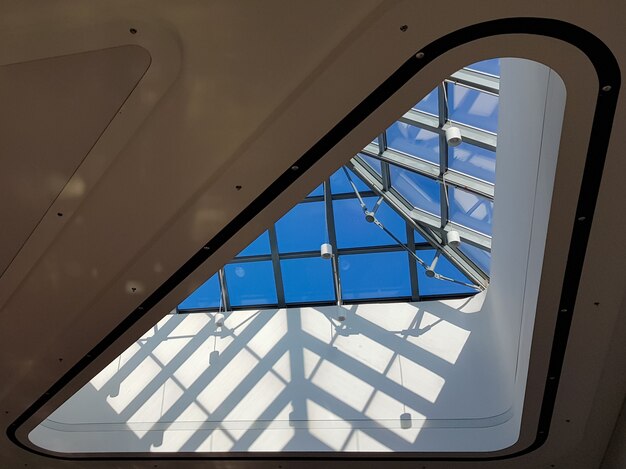 Sufit o konstrukcji stalowej wykonany z metalu i szkła na tle błękitnego nieba. Nowoczesna elegancka architektura zakupów w centrum handlowym.