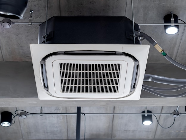 Sufitowa dekoracja klimatyzatora kasetonowego w pobliżu świateł punktowych na betonowej konstrukcji wnętrza w stylu loftu Sufitowy klimatyzator z systemem wentylacji