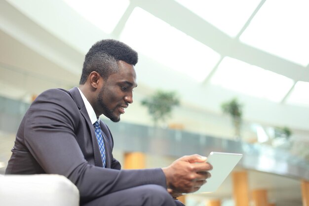 Sukcesy african american biznesmen pracuje na swoim touchpadzie.