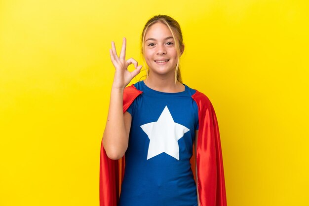 Super bohater mała dziewczynka na białym tle na żółtym tle pokazując znak ok palcami