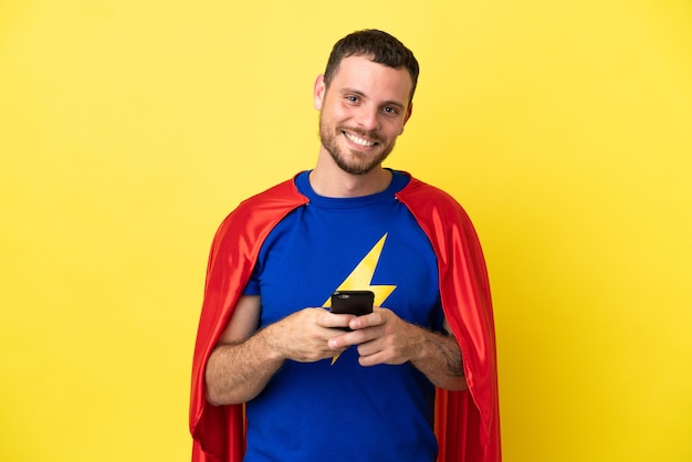 Super Hero brazylijski mężczyzna na białym tle na żółtym tle wysyłający wiadomość za pomocą telefonu komórkowego