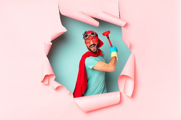 Superbohater z przedmiotami łazienkowymi za połamaną papierową ścianą