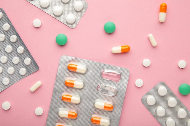 Suplementy i pigułki blistry na różowym tle Farmaceuci i kliniki
