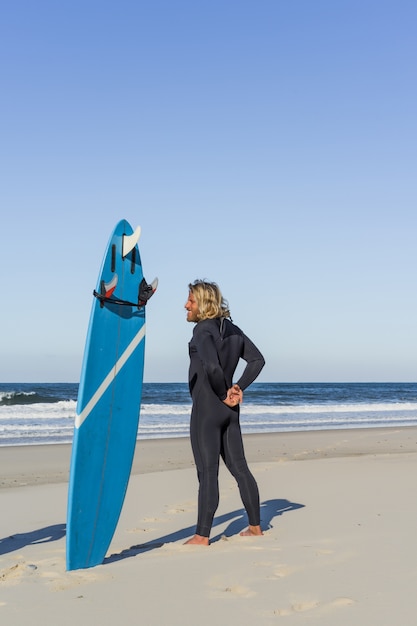 surfer człowiek na plaży rozgrzewkę przed surfingu, Surf Man w kombinezonie z deski surfingowej na oceanie