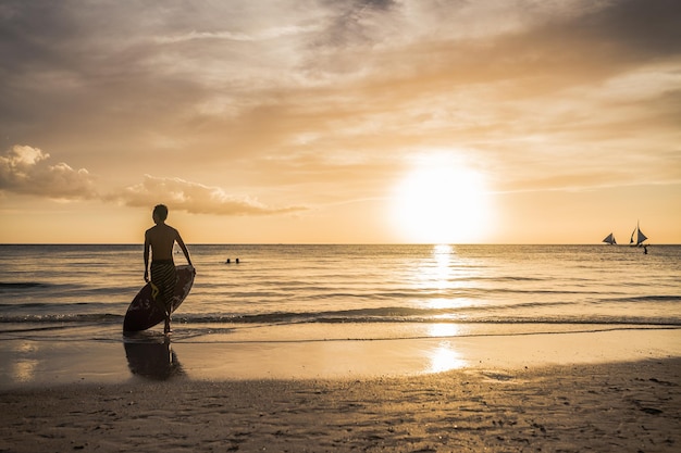 Surfer na plaży o zachodzie słońca.