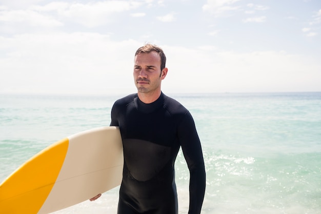 Surfer spaceru na plaży z deską surfingową