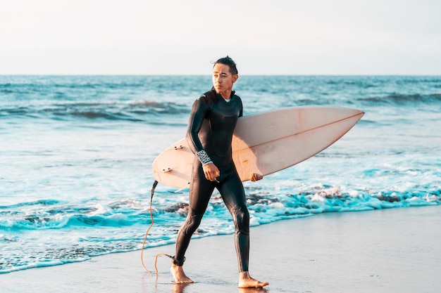 surfer spacerujący po plaży z deską surfingową