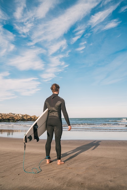 Surfer wchodzi do wody ze swoją deską surfingową.